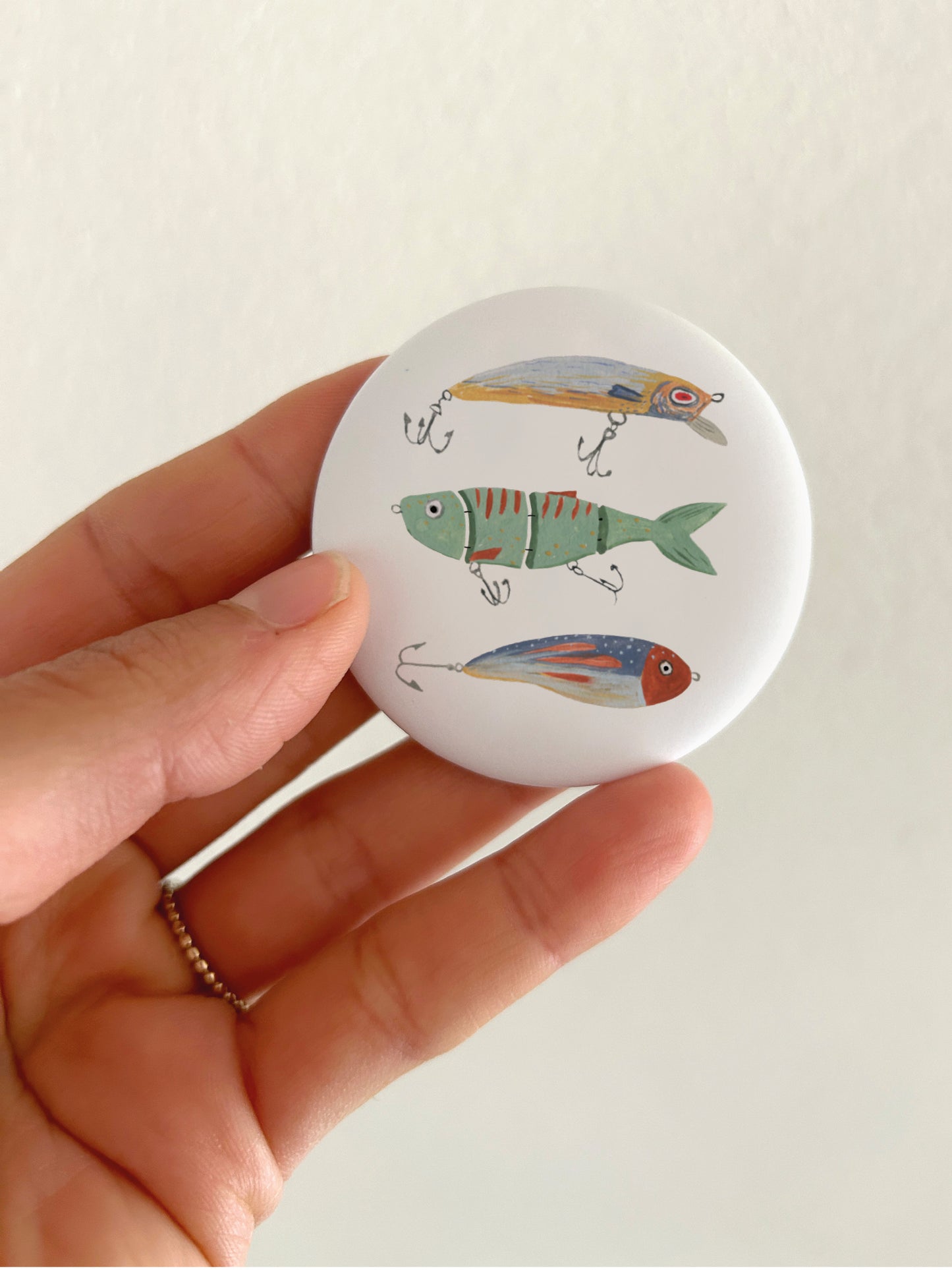 Angelköder-Magnet. Handgemalte Illustration auf rundem Kühlschrankmagnet.