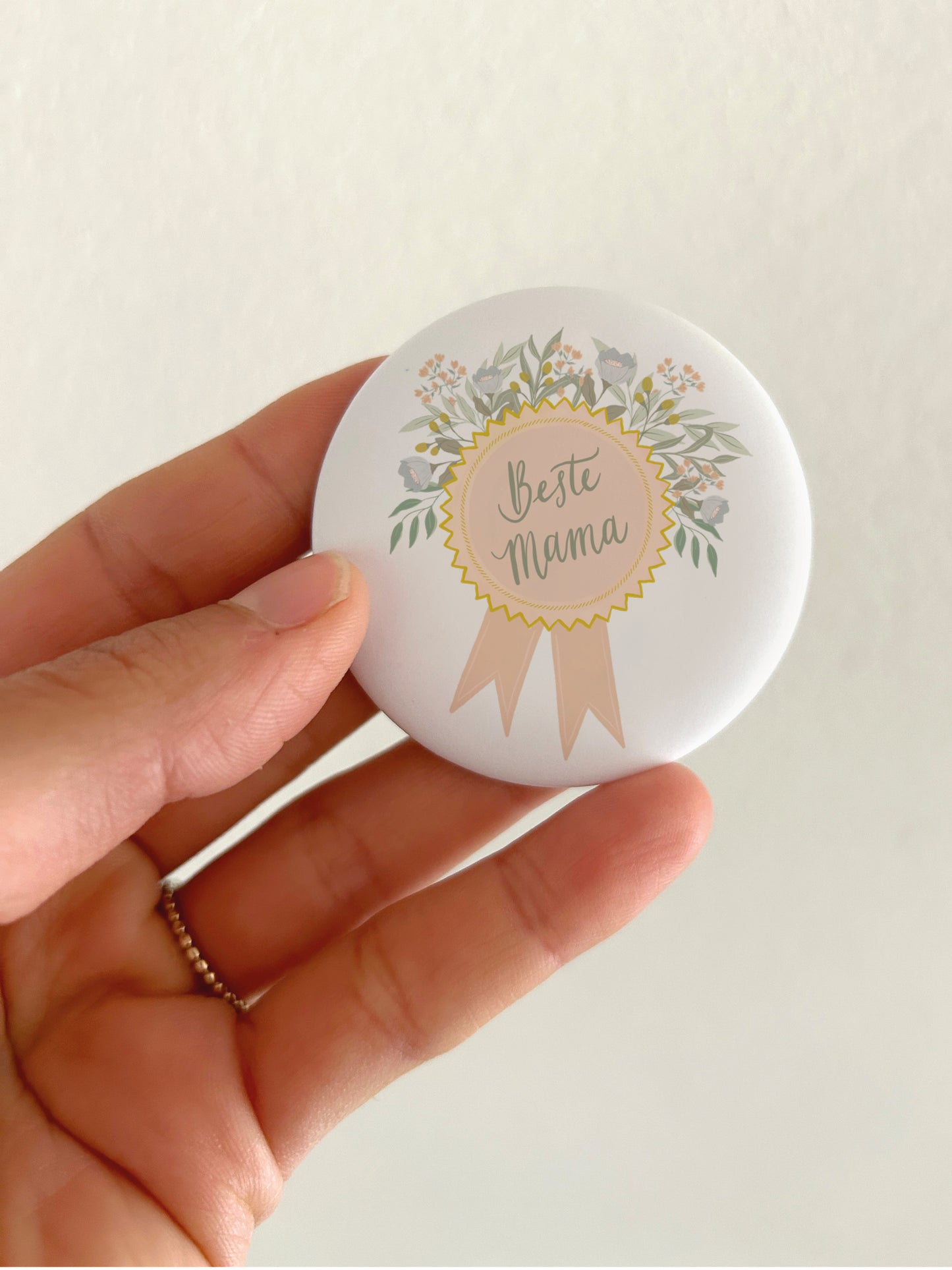 Großer Muttertags-Magnet Beste Mama mit 55mm Durchmesser als liebevolle Deko für die Küche. Ein runder, matter Kühlschrankmagnet im edlen Medaillen-Design wird als Größenvergleich vor einem hellen Hintergrund in einer Hand gehalten, um die reale Produktgröße und die reflexionsfreie, kratzfeste Oberfläche zu zeigen.