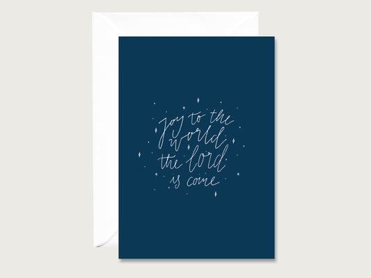 Dunkelblaue Karte mit feinem, weißen handgeschriebenem Schriftzug "Joy to the World the Lord is come". Drumherum sind weiße Sternchen platziert.
