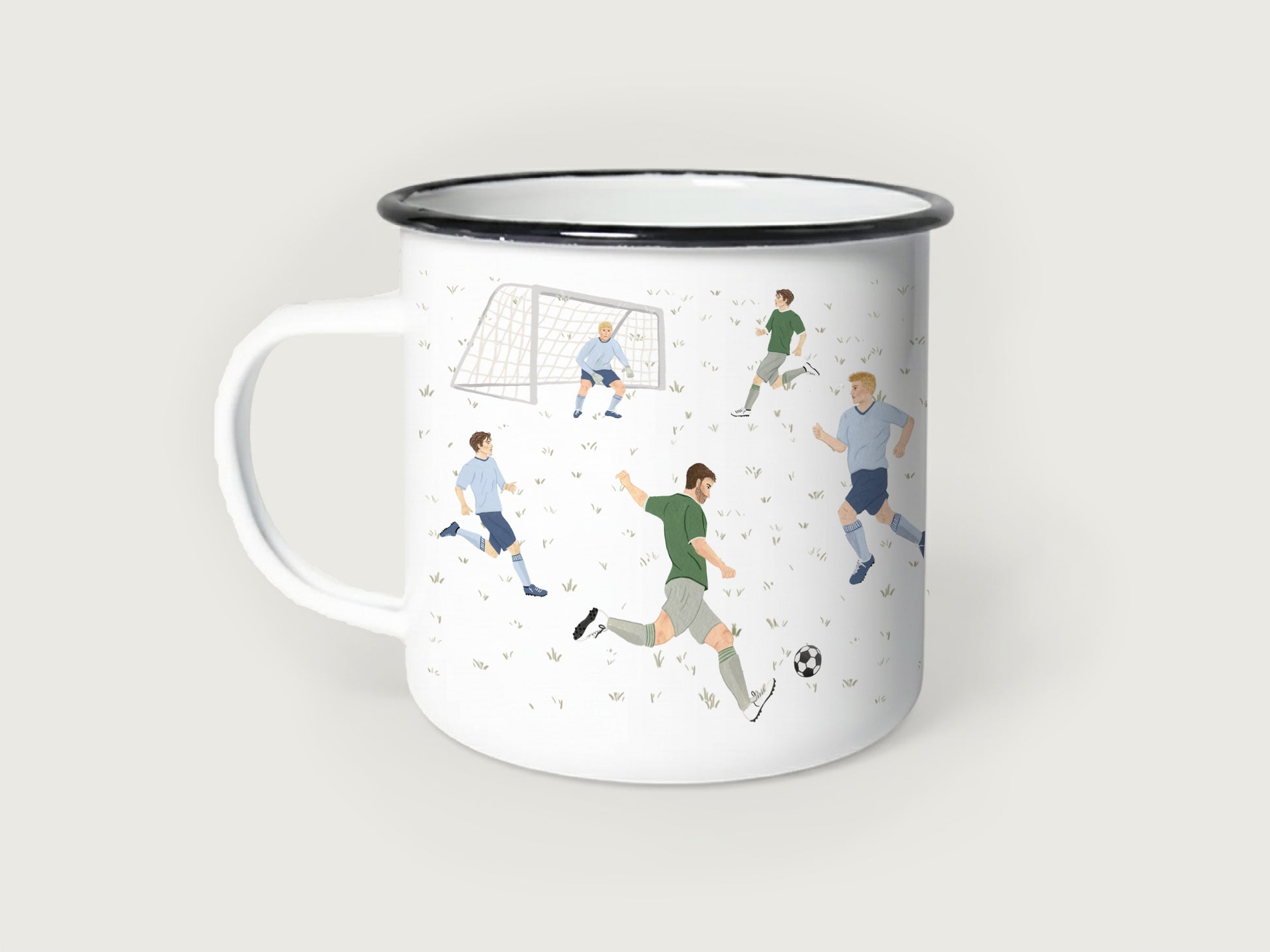 Weißer Emaillebecher mit schwarzem Rand, bedruckt mit einer handgemalten Fußball-Spielszene auf einem feinen Rasenmuster. Zu sehen sind mehrere Fußballspieler in grünen und hellblauen Trikots, ein Torwart im Fußballtor und ein klassischer Fußball beim Torschuss.