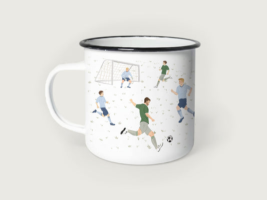 Weißer Emaillebecher mit schwarzem Rand, bedruckt mit einer handgemalten Fußball-Spielszene auf einem feinen Rasenmuster. Zu sehen sind mehrere Fußballspieler in grünen und hellblauen Trikots, ein Torwart im Fußballtor und ein klassischer Fußball beim Torschuss.