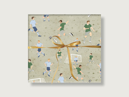Geschenk mit Fußball-Geschenkpapier. Da sind auf grünem Hintegrund verschiedene Fußballer zweier Mannschaften und ein Tor. Es ist eine Fußballszene nachgestellt. 