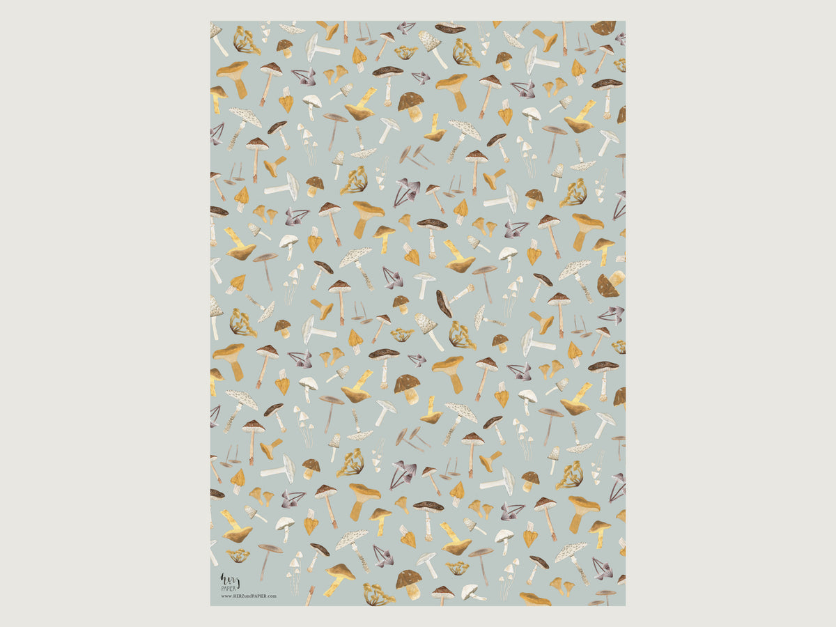 Das ausgebreitete Geschenkpapier mit herbstlichen Pilzillustrationen liegt glatt auf dem Tisch und zeigt das gleichmäßige Muster auf hellblauem Grund.