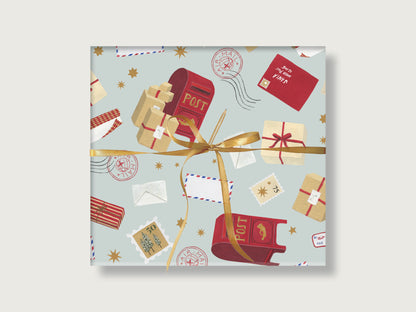 Geschenk mit geschmackvollem, weihnachtlich illustriertem Geschenkpapier  mit Weihnachtspost-Motiven, wie roten Briefkästen, Paketen und Briefen auf zartblauem Hintergrund, verpackt mit goldener Schleife.  