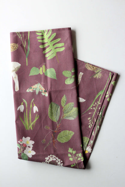Gefaltetes Geschirrtuch aus Leinenmix mit botanischem Pflanzen- bzw. Naturmotiv auf mauve-farbenem hintergrund.