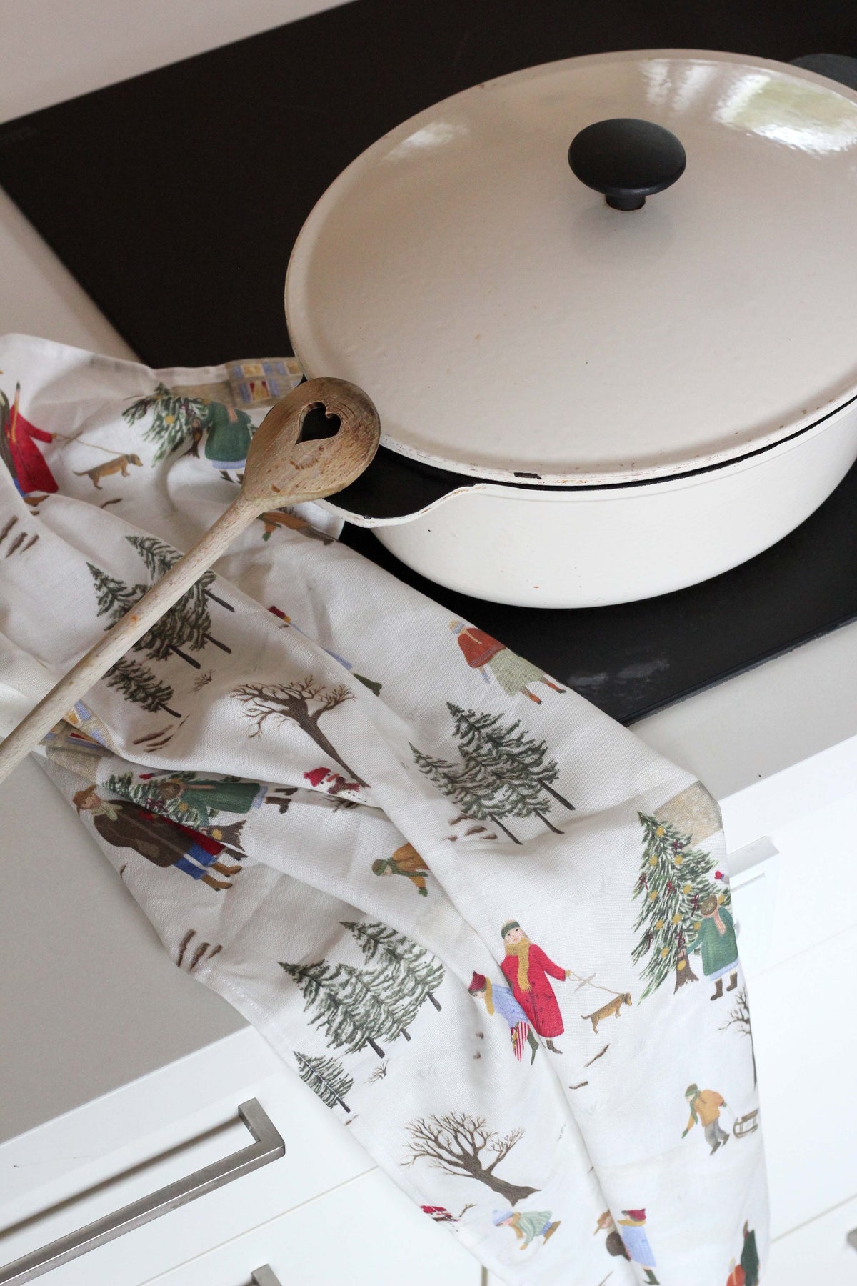 Leinen Abtrockentuch als weihnachtliche Deko in der Küche neben Bräter und Kochlöffel.