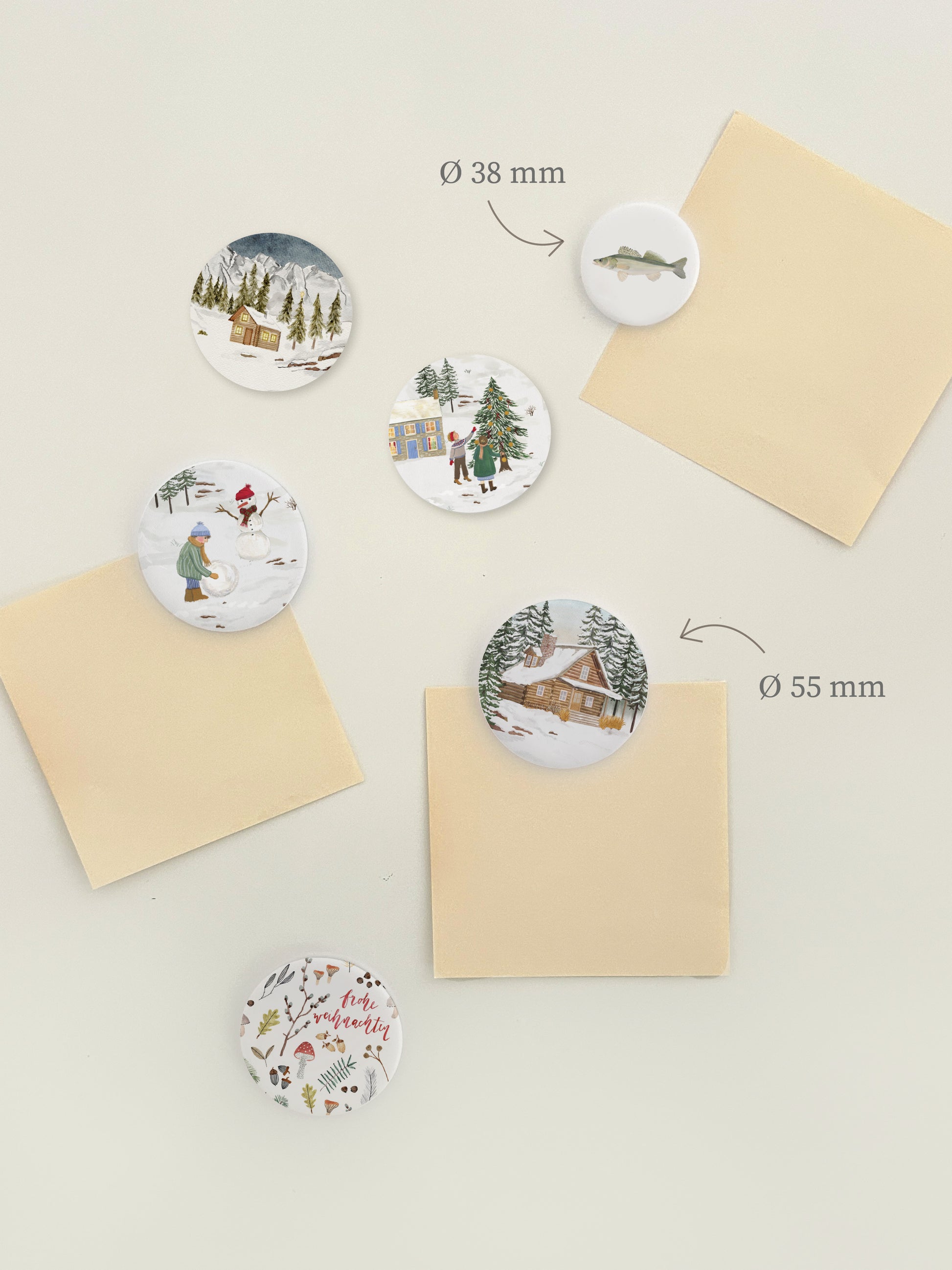 Magnetwand mit verschiedenen, runden Magnetbuttons mit weihnachtlichen Motiven, wie zum Beispiel Holzhütten im Winterwald, Kinder beim Baumschmücken oder Schneemann bauen oder Naturcollagen mit "Fröhliche Weihnachten"-Aufschrift.