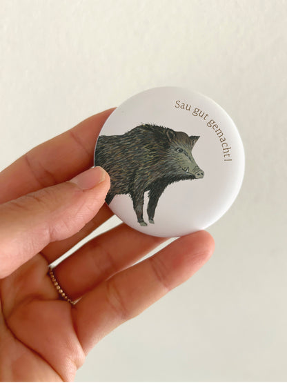 Runder Magnet-Button mit Wildschweinmotiv und dem Text "sau gut gemacht". 