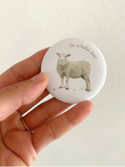 Großer Motivations-Magnet Du schafst das mit 55mm Durchmesser als liebevolle Deko für die Magnetwand in der Küche oder Schule. Ein runder, matter Schaf-Kühlschrankmagnet wird als Größenvergleich in einer Hand gehalten, um das spiegelungsfreie Schutzlaminat anschaulich zu präsentieren.