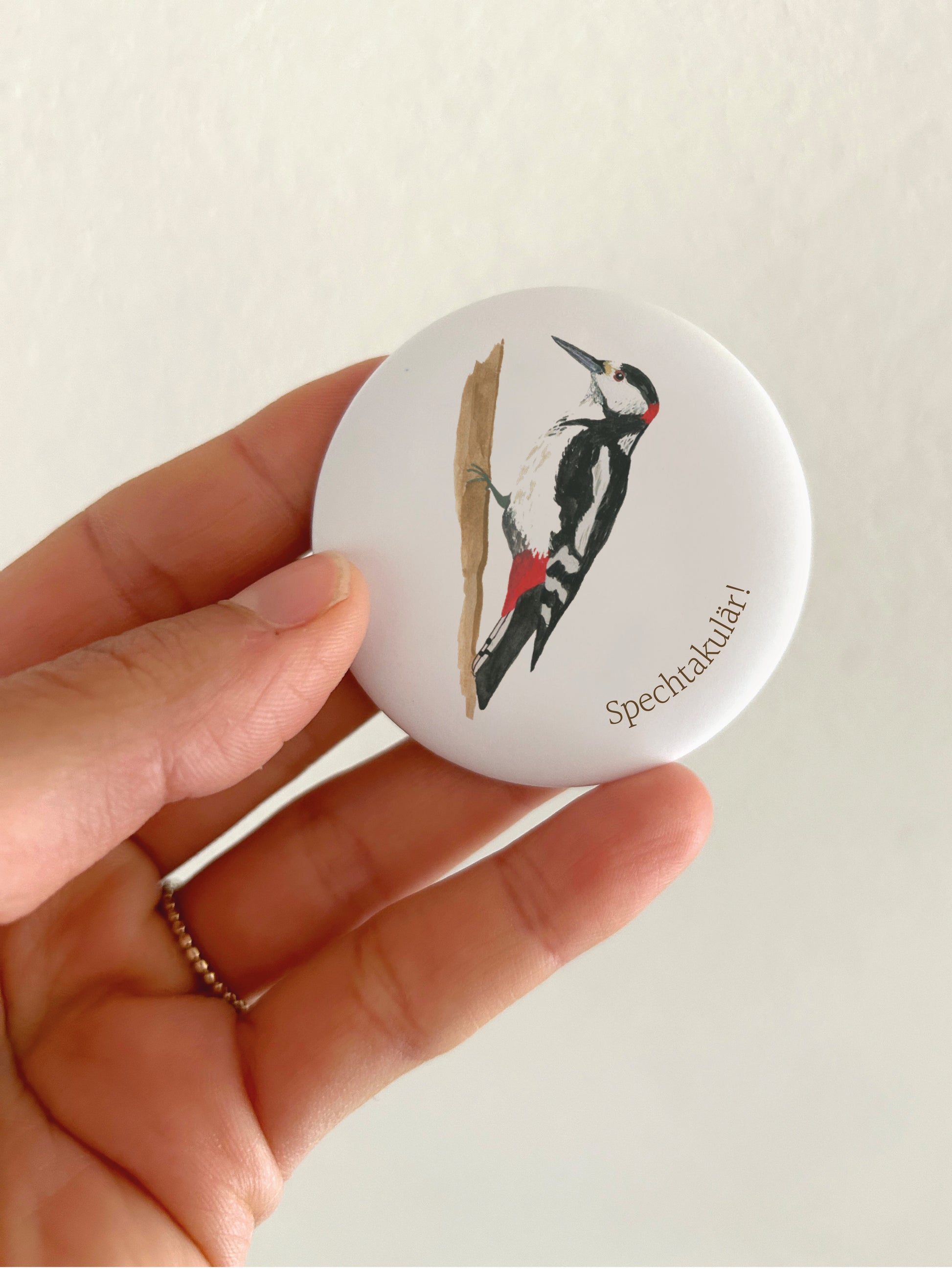 Großer Motivations-Magnet Spechtakulär mit 55mm Durchmesser als witzige Deko für das Whiteboard oder die Magnetwand im Büro. Ein runder, matter Kühlschrankmagnet wird als Größenvergleich in einer Hand gehalten, um das kratzfeste, spiegelungsfreie Schutzlaminat zu zeigen.