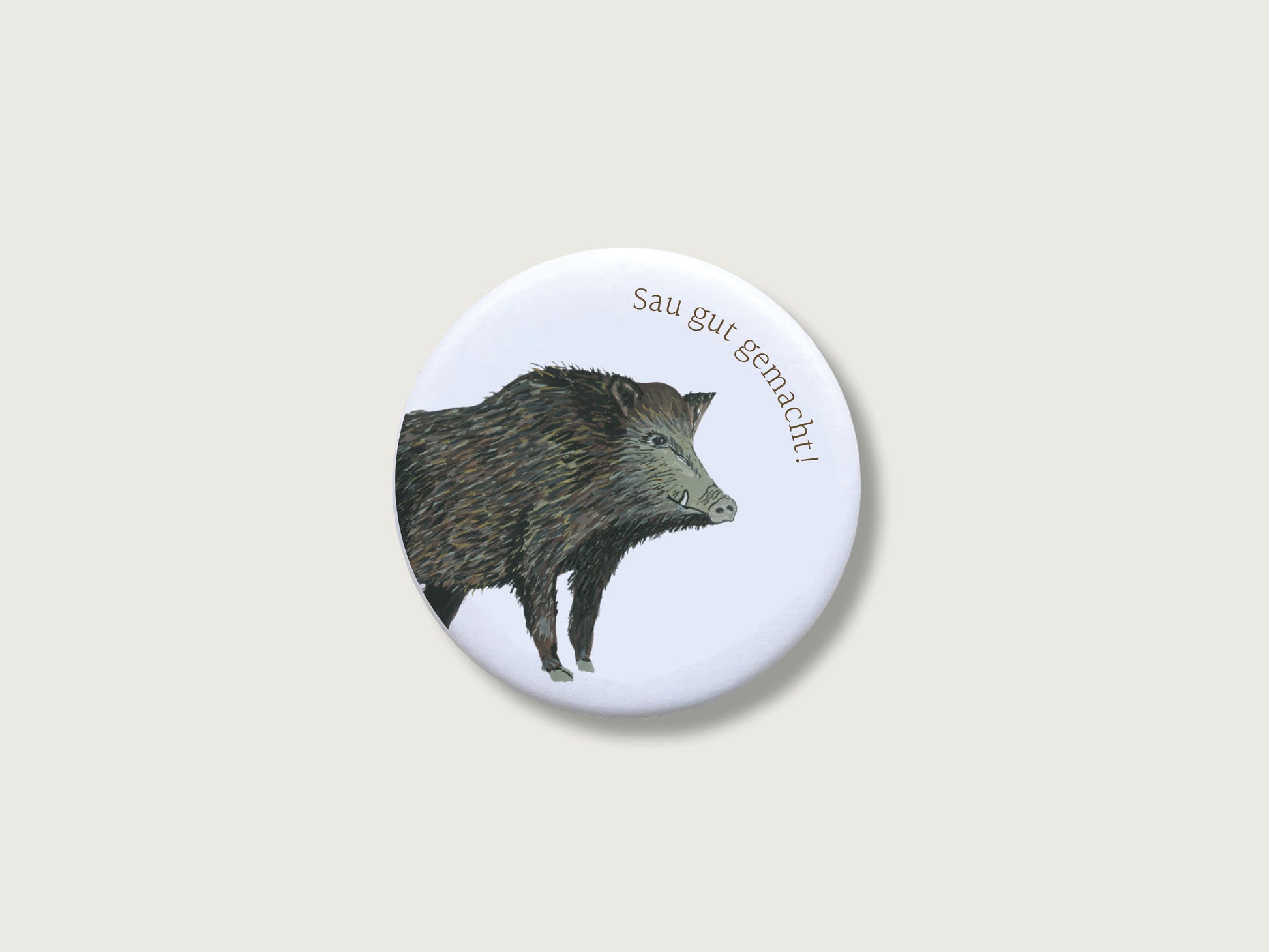 Runder, weißer Kühlschrankmagnet mit handgemaltem Wildschweinmotiv und dem Spruch "Sau gut gemacht" als Mitbringsel für den bestandenen Jagdschein, Test, Führerschwein, Prüfung.