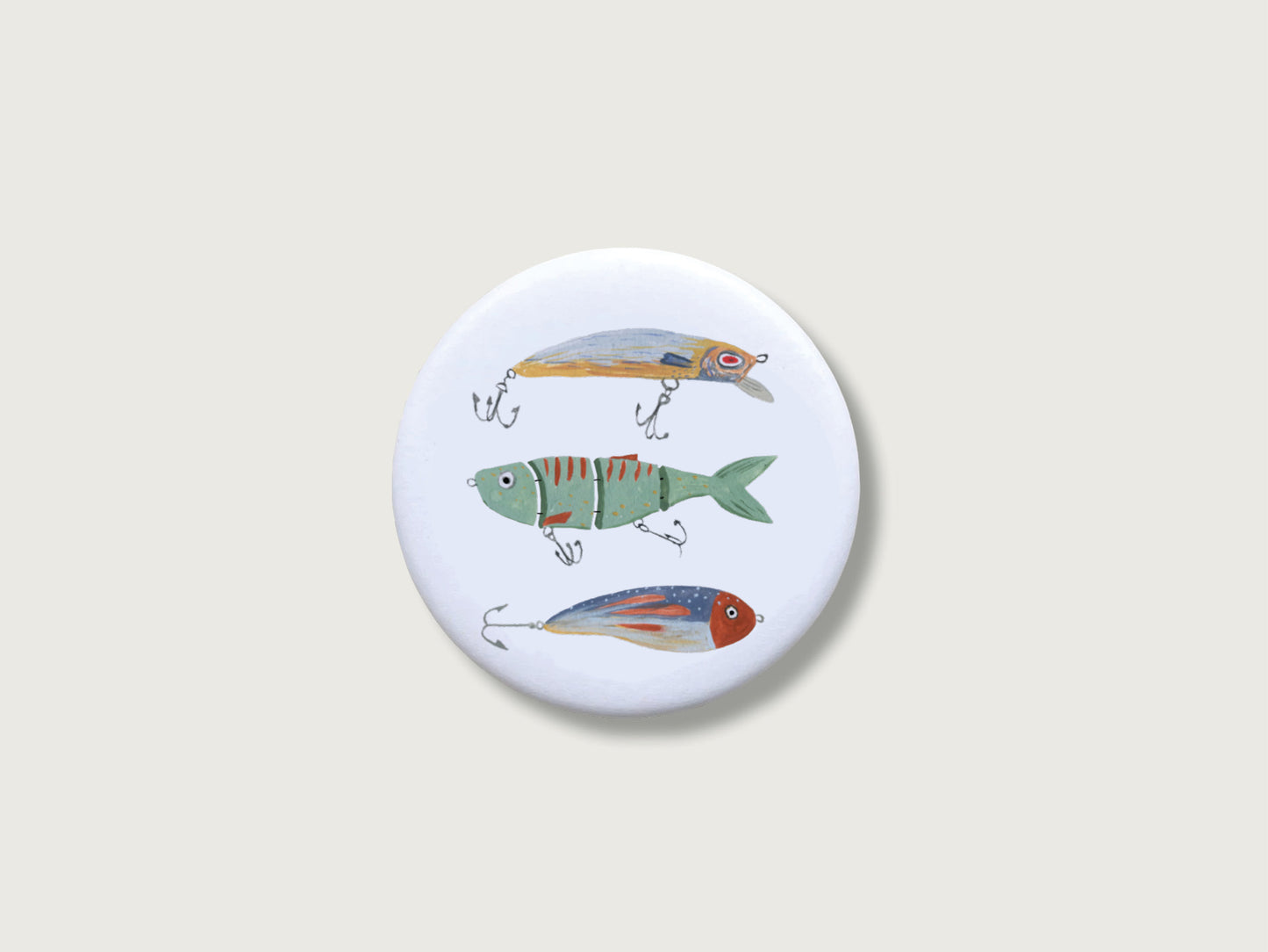 Runder, weißer Kühlschrankmagnet in Form eines Buttons mit handillustrierten Wobbeln und Fisch-Ködern.