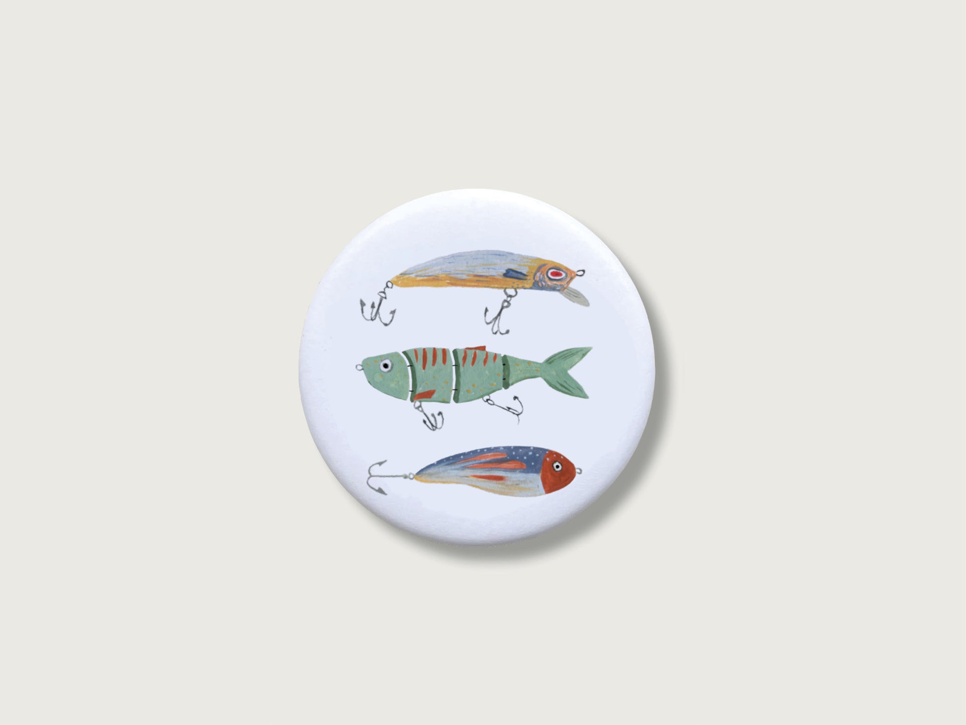 Runder, weißer Kühlschrankmagnet in Form eines Buttons mit handillustrierten Wobbeln und Fisch-Ködern.