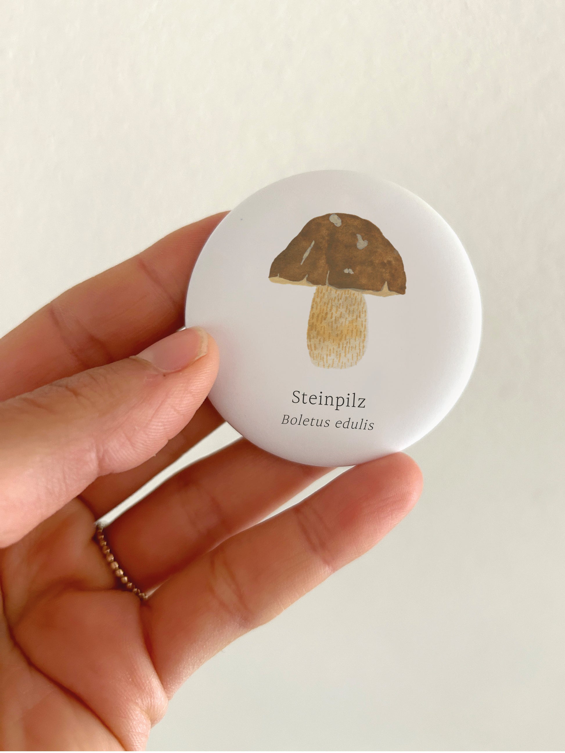 Stilvolles Geschenk für Pilzsammler und Naturliebhaber: Runder, weißer Kühlschrankmagnet mit einer detaillierten Handillustration eines Steinpilzes inklusive der wissenschaftlichen Beschriftung Boletus edulis. Das botanische Motiv aus Große Magnete Steinpilz.jpg liegt zentriert auf einem schlichten, hellen Hintergrund.