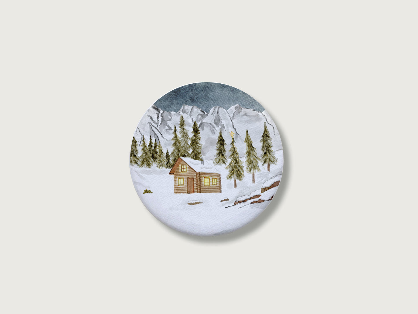 Gemütliches Geschenk zur Adventszeit und für Bergfans: Runder, weißer Kühlschrankmagnet mit einer detailreichen, handillustrierten Winterlandschaft, bestehend aus einer verschneiten Holzhütte mit leuchtenden Fenstern, tiefgrünen Tannen und einer majestätischen, schneebedeckten Bergkulisse. Das weihnachtliche Motiv von Großer-Magnet-Weihnachten1.jpg befindet sich mittig auf einem schlichten, neutralen, hellen Hintergrund.