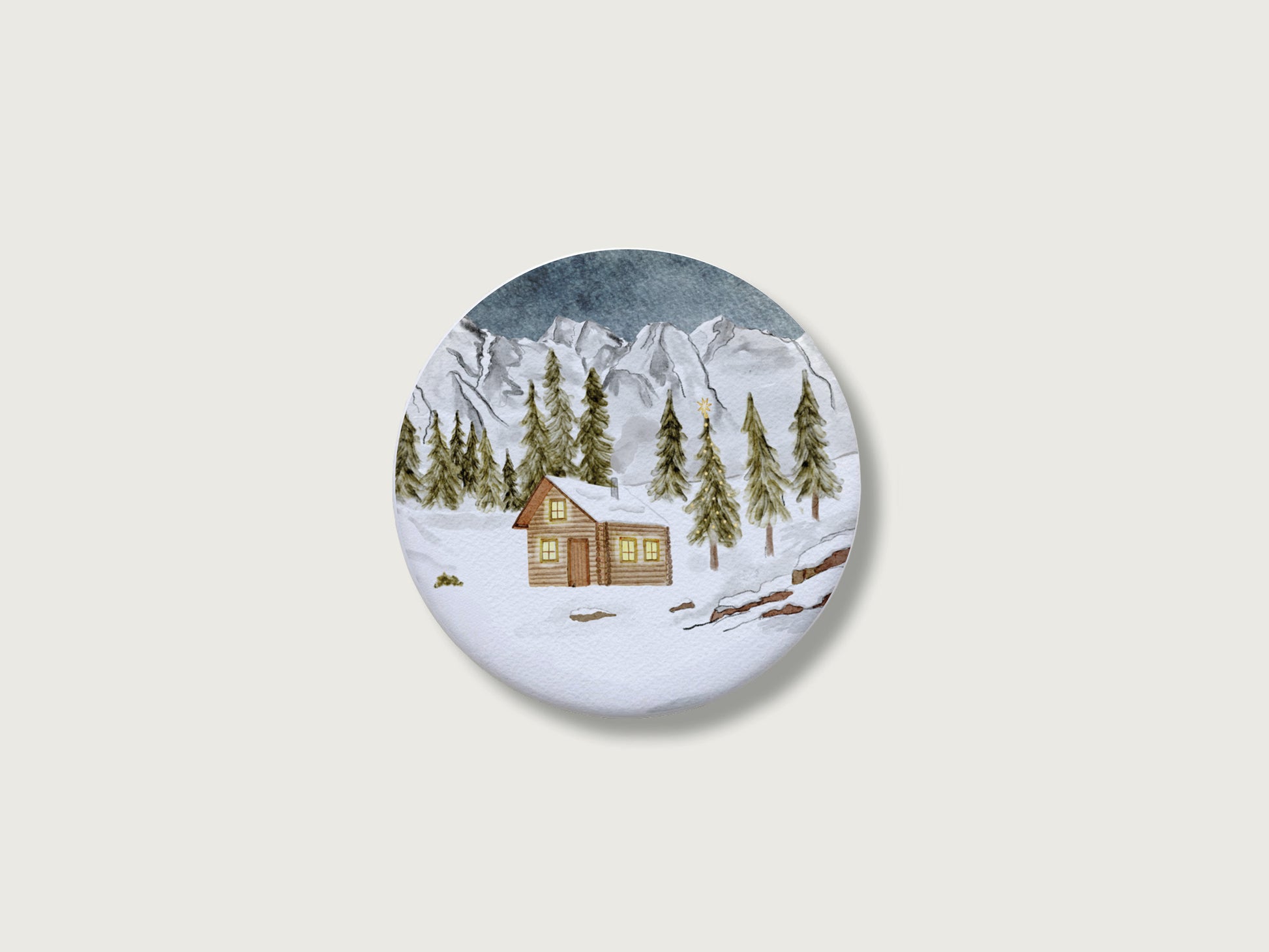 Gemütliches Geschenk zur Adventszeit und für Bergfans: Runder, weißer Kühlschrankmagnet mit einer detailreichen, handillustrierten Winterlandschaft, bestehend aus einer verschneiten Holzhütte mit leuchtenden Fenstern, tiefgrünen Tannen und einer majestätischen, schneebedeckten Bergkulisse. Das weihnachtliche Motiv von Großer-Magnet-Weihnachten1.jpg befindet sich mittig auf einem schlichten, neutralen, hellen Hintergrund.