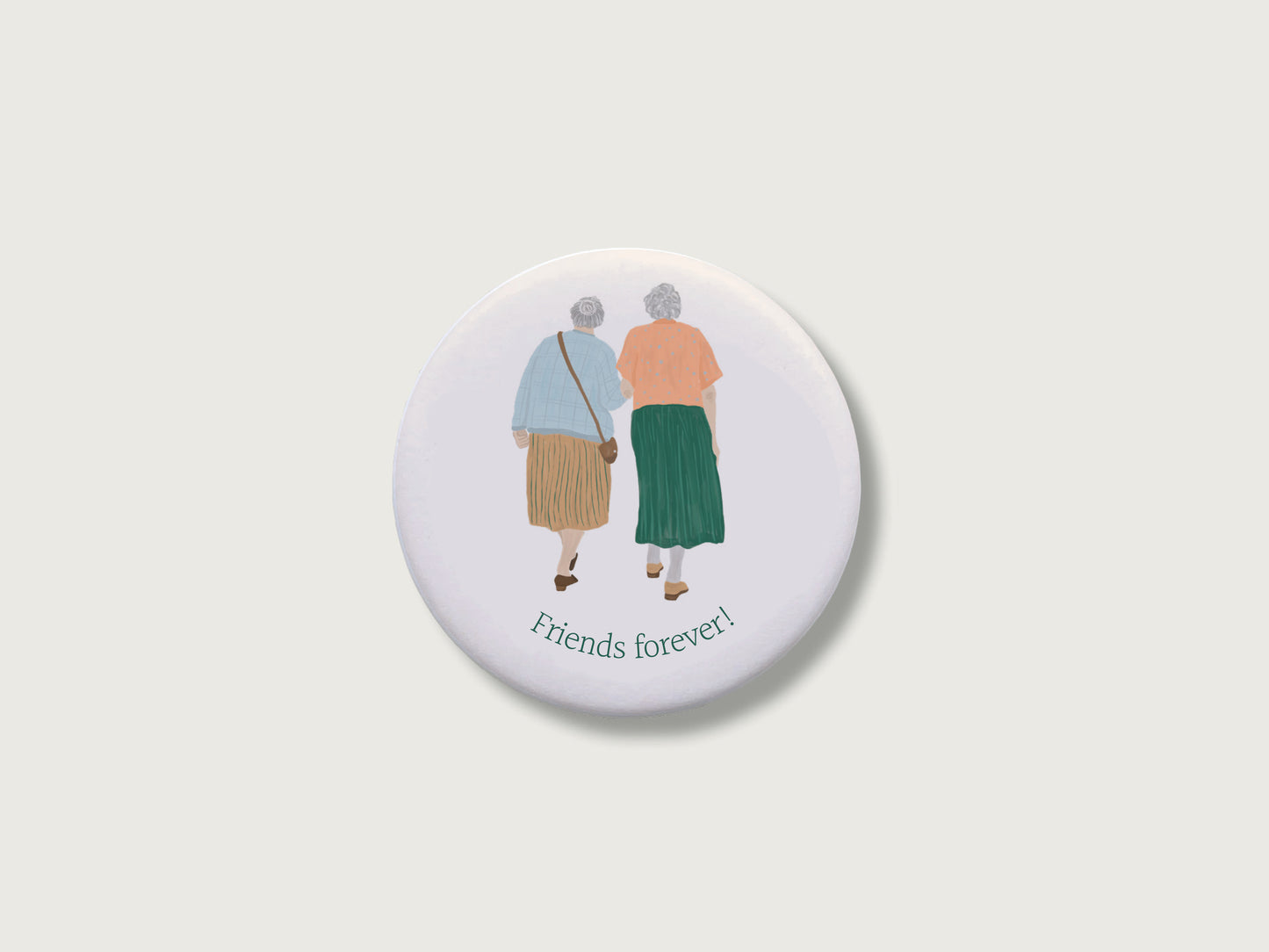 Persönliches Geschenk für die beste Freundin: Runder, weißer Kühlschrankmagnet mit Spruch Friends forever und einer handillustrierten Grafik von zwei älteren Frauen, die eng vertraut Arm in Arm von hinten zu sehen sind. Das Motiv im analogen Zeichenstil ist mittig auf einem schlichten, neutralen, hellen Hintergrund platziert.