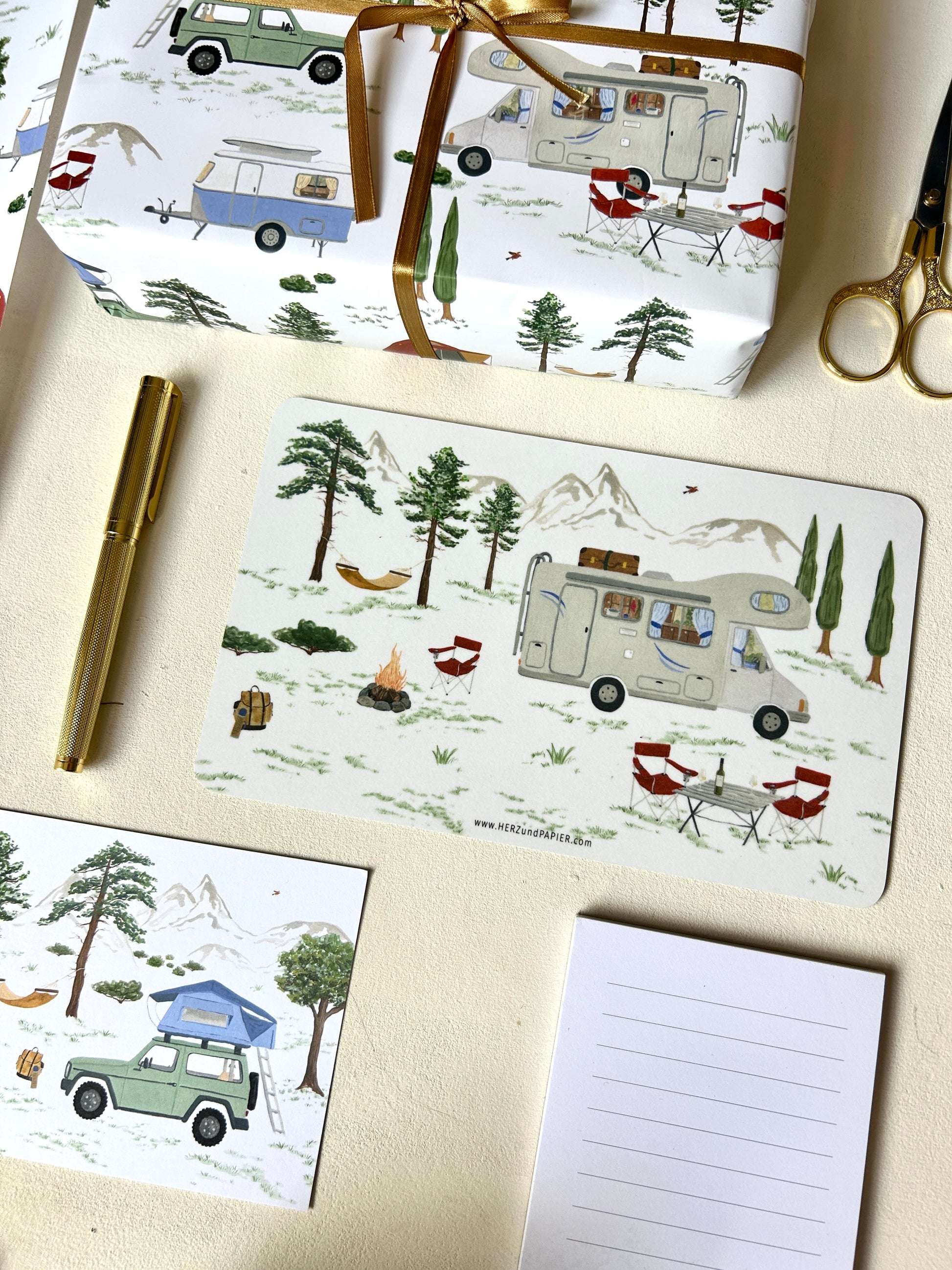 Robustes Melamin-Frühstücksbrettchen für Camper mit detailreichen Aquarell-Motiven von Wohnmobil, Lagerfeuer und Natur, angerichtet mit passender Camping-Papeterie. Die Postkarte und das Geschenkpapier zeigen auch einen Jeep mit Dachzelt und einen Wohnwagen.