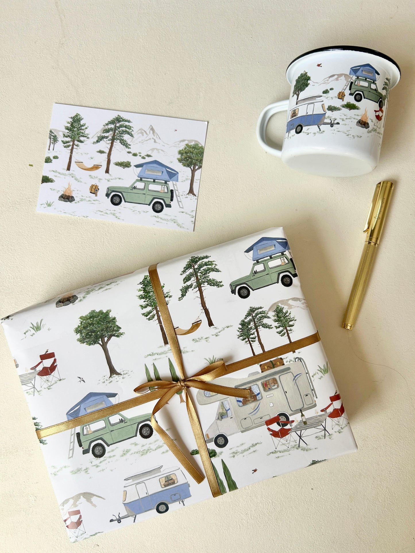 Camping-Geschenkset bestehend aus liebevoll verpacktem Geschenk, einer Postkarte mit Dachzelt-Motiv und einer Emaille-Tasse als praktisches Campinggeschirr. Alle Produkte zeigen ein Camping-Motiv mit dem Fokus auf dem Offroad-Fahrzeug mit Dachzelt.