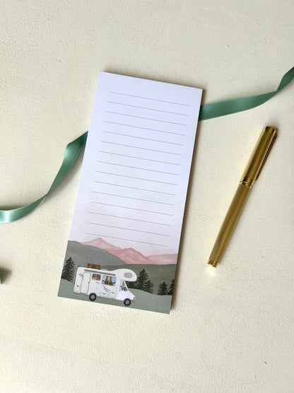 Linierter Notizblock im Camping-Design mit handgemalter Aquarell-Illustration eines Wohnmobils vor einer Bergkulisse, elegant dekoriert mit goldenem Stift.