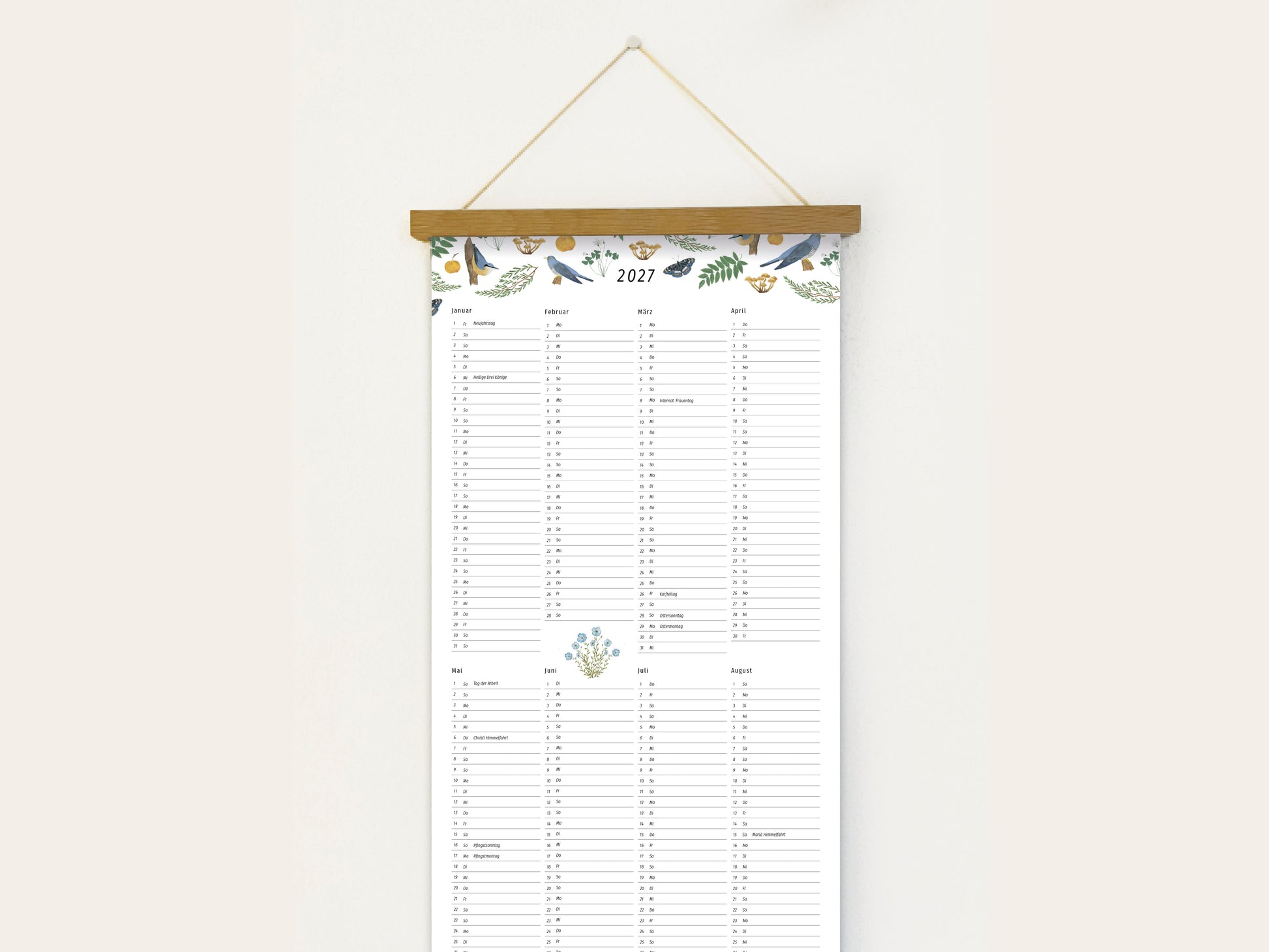 Langformatiger Wandplaner 2027 mit handillustrierten Vögeln, Schmetterlingen und botanischen Aquarell-Motiven, aufgehängt an einer Holzleiste vor einer weißen Wand.