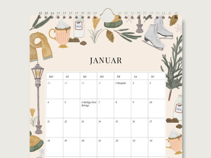 Aufgeschlagene Monatsseite Januar des Wandkalenders auf mattem Naturpapier mit datierten Tagesfeldern, Feiertagen und handillustrierten Wintermotiven wie Schlittschuhen und Kakaotasse.