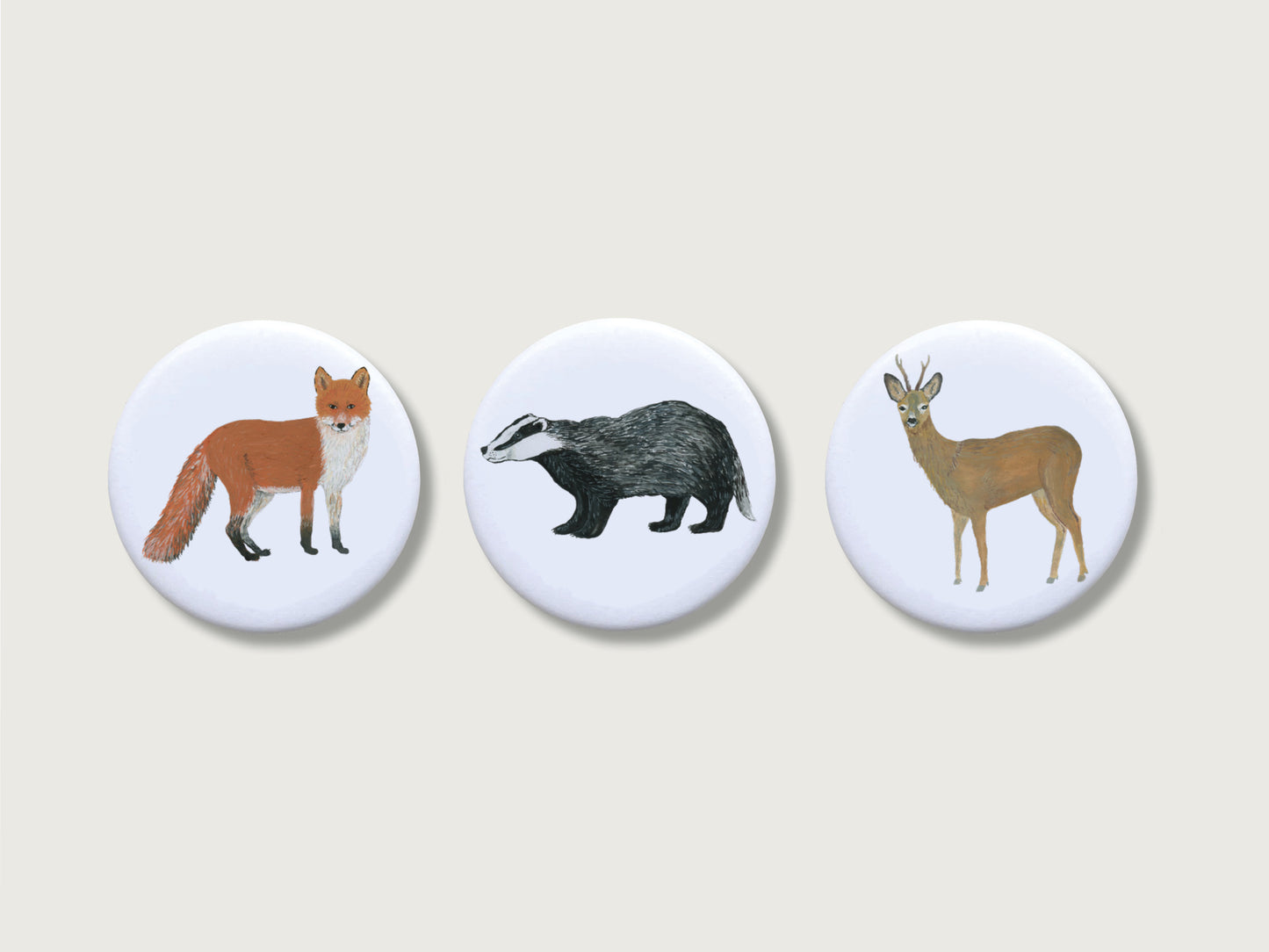 Drei runde Kühlschrankmagnete mit matten Waldtier-Illustrationen (Fuchs, Dachs und ein Rehbock mit Geweih) auf hellem Hintergrund. Die Illustrationen der Tiere wurde von Hand gemalt. 