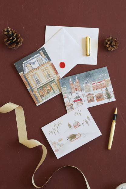 Drei Weihnachtskarten mit Illustrationen von Stadt- ländlicher Landschaft. Alle drei weihnachtlichen Motiven zeigen eine Szene im Schnee. Mal ein Stadthaus, dann ein Geschäft oder einen Weihnachtsmarkt oder ein Schwedenhaus. 
