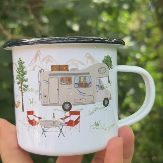 Eine Hand hält eine weiße Emaille-Tasse vor einem weich gezeichneten, grünen Waldhintergrund und dreht sie langsam um 360 Grad. Dabei wird das vollständige, umlaufende und detailreiche Design aus handgemalten Camping- und Naturmotiven wie Lagerfeuer, Rucksack, Bäumen und Outdoor-Ausrüstung sichtbar.